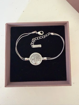Silverfärgat armband med livets träd - Vackert silverfärgat armband med ett runt hänge som föreställer livets träd. Köpt för £25 på TK Maxx🤗Aldrig använd, fin att ge som present