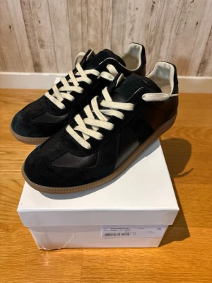 Maison Margiela - Maison Margiela i svart. De har en klassisk siluett med paneler i mocka och textil, perfekta för en clean och stilren look. Kvitto finns!