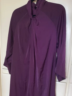 Inwear långklänning med draperad krage stl 40 - Säljer en elegant lila långklänning Inwear Copenhagen 1969 med draperad krage och trekvartsärm. Klänningen har en lös passform och ett mjukt, lätt material som faller snyggt. Perfekt för dig som vill ha en stilren och bekväm look.