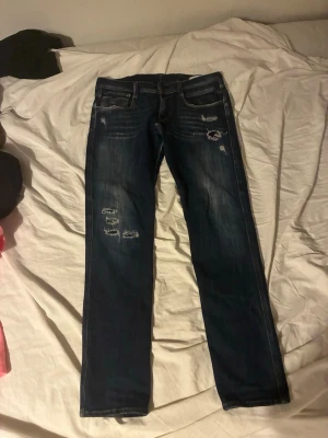 Mörkblå replay anbass jeans med slitningar - Säljer ett par replay anbass slimfit jeans med slitningar. Säljer pga urväxta. Vid snabb affär kan vi diskutera priset. Hör av er vid någon fundering.