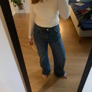 Säljer ett par snygga blå jeans med hög midja. De har en klassisk femficksdesign och stängs med dragkedja och knapp. Perfekta för en avslappnad vardagslook!