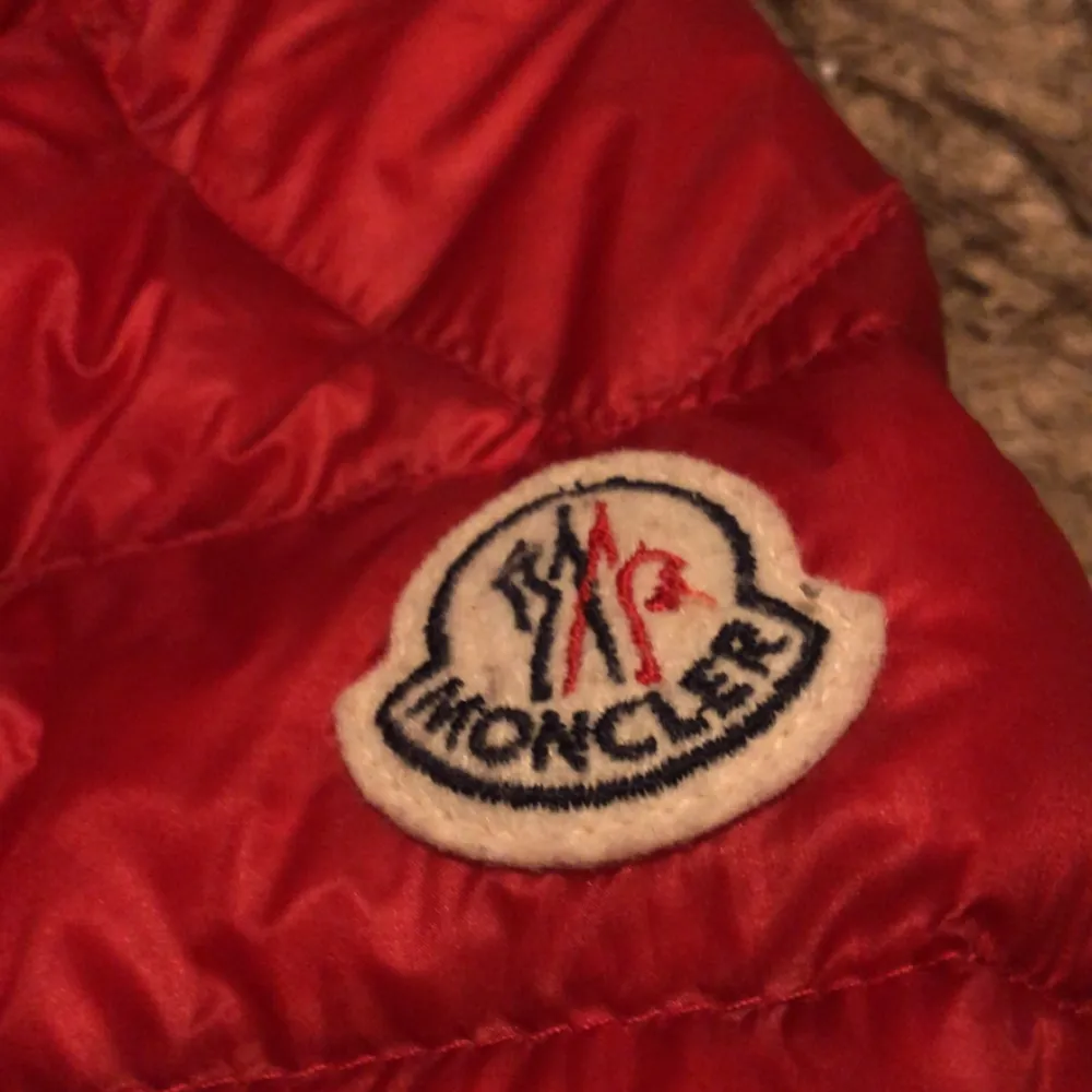 Säljer en snygg röd dunjacka från Moncler. Jackan är i nyskick och har en stilren design med dragkedja och Monclers logga på ärmen. Perfekt för höst och vinter, håller dig varm och trendig. Den har en normal passform och är långärmad. Passar perfekt för både vardag och fest!. Jackor.