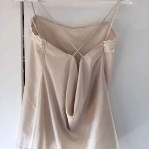 Beige siden top with x formed straps in the back and cute spetts in the front. Has never been used.