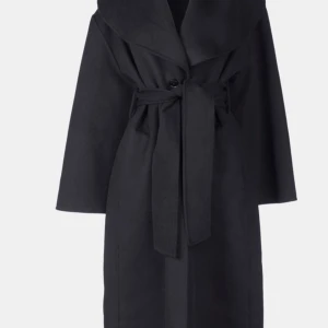 Svart lång kappa i 100% ull - Termoli Coat Long är en tidlös kappa med bälte gjord av en lyxig dubbelsidig ullblandning. Den har en chic sjalkrage, diskreta sidosömsfickor och stängning med en knapp för en minimalistisk, sofistikerad look.