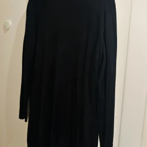 Svart lång kofta från Bon'A Parte - Säljer en stilren svart lång kofta från Bon'A Parte. Den har långa ärmar och knappar framtill, perfekt för höst och vinter. Koftan är i ett mjukt material som känns skönt mot huden. Passar både till vardags och lite finare tillfällen.