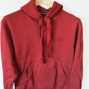 Acne studios hoodie - Säljer denna röda acne studio hoodien från collektionen ”ferrie face” den är i fint skick och sparsamt använd. Deras storlekar är lite oversized, så M bör passa som L Hör av dig vid funderingar!!