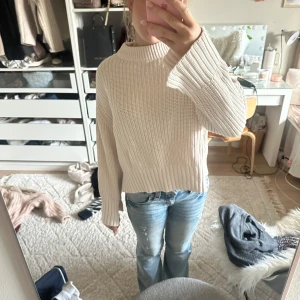 Beige stickad tröja - Säljer en mysig beige stickad tröja med ribbade detaljer vid ärmslut och nederkant. Tröjan har en avslappnad passform och långa ärmar