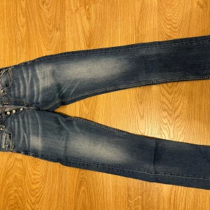 Blå jeans från Replay - Snygga blå jeans från Replay med en klassisk femficksdesign och knappar i gylfen. Jeansen har en lätt tvättad look och är perfekta för en avslappnad stil. Märket Replay syns tydligt på etiketten vid midjan. Skick 9/10! Pris kan diskuteras