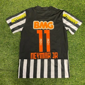 Svart och vit fotbollströja med Neymar Jr - Snygg svart och vit randig fotbollströja med Neymar Jr och nummer 11 på ryggen. Tröjan har korta ärmar med Netshoes-logga och BMG-sponsor i orange. Perfekt för fotbollsfans!