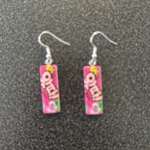 Rosa örhängen med godismotiv - Unika örhängen med ett färgglatt godismotiv i rosa och grönt. Perfekta för att lägga till en lekfull touch till din stil. De hänger från en enkel krok och är lätta att bära.