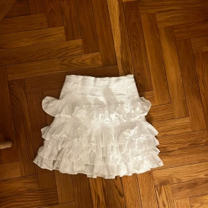 Vit volangkjol från H&M - Säljer en söt vit volangkjol från H&M i storlek XS. Kjolen har flera lager av volanger som ger en lekfull och romantisk känsla. Perfekt för sommarens alla tillfällen. 🕊️