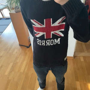 Morris Stickad Tröja - Säljer en sjukt fet unik svart stickad tröja från Morris. Tröjan har Storbritanniens flagg på sig och är gjord i ett tjockt material. Den är i bra men använt skick och i storlek L men kan även passa strl M. Hör gärna av er vid frågor eller funderingar!!