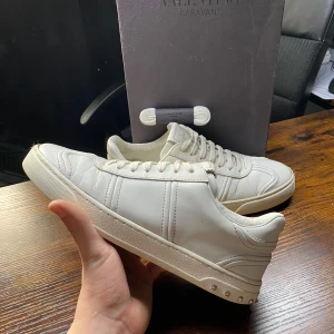 Valentino Flycrew - Stilrena och lyxiga Valentino Flycrew sneakers i vitt! En perfekt kombination av komfort och exklusiv design. Notera att en nit saknas, men skorna behåller ändå sin eleganta look.  | Färg: Vit ⚪✨ | Skick: Bra skick, men en nit saknas ⚠️ | Modell: Flycrew 🏆 | Storlek: 41👌 | Tillbehör: Box och snören👟  🚚 |Leverans: Skickas snabbt via PostNord eller Instabox 📬📦 | 💬 Skicka ett meddelande vid frågor!