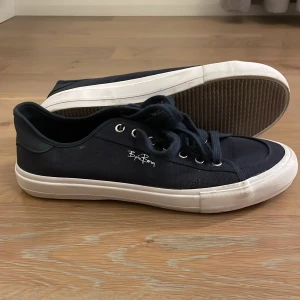 Svarta sneakers från Björn Borg - Snygga mörkblå sneakers från Björn Borg med vit sula och snörning. Tillverkade av återvunnet material, vilket gör dem till ett miljövänligt val. Perfekta för en avslappnad stil.
