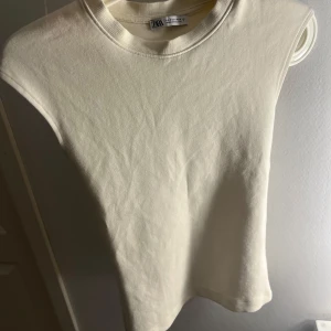  topp från Zara - Säljer en stilren topp från Zara. Perfekt för varma dagar eller som ett basplagg i garderoben. Toppen har en rund halsringning och är gjord i ett mjukt material.