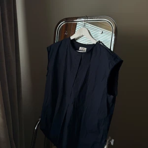 Acne Studios top - Snygg svart ärmlös skjorta från Acne Studios med en stilren design. Den har en dragkedja på axeln och en lös passform som ger en avslappnad look. Perfekt för en minimalistisk stil.