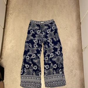 Tunn sommarbyxa i viskos  - Säljer ett par superfina sommar byxor från Flash Woman,  det är mörkblå med vita mönster samt snörning och resår i midjan. Det är i storlek M och är i viskos. ⭐️