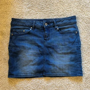 Blå jeanskjol från edc - Snygg blå jeanskjol som jag aldrig använt! Midjemåttet rakt över är 38 cm. Längden på kjolen är 35 cm!