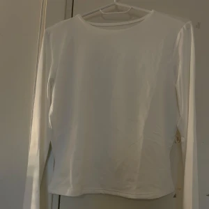 Vit långärmad tröja - Säljer en enkel och stilren vit långärmad tröja. Perfekt basplagg för alla tillfällen. Tröjan har en rund halsringning och är gjord i ett mjukt material för extra komfort.