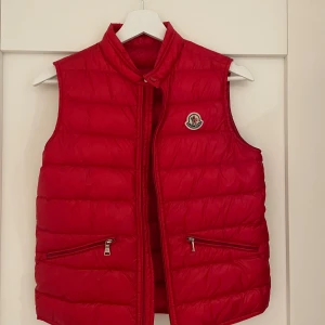 Moncler väst röd - Säljer denna röda Moncler väst. Äktehetsbevis finns skriv privat! Inga defekter, storleken är 12/152 som barn men kan tolkas som XS. Pris kan diskuteras
