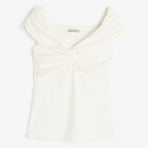 Vit offshoulder topp - Elegant vit offshoulder topp med draperad design och knutdetalj framtill. Perfekt för en stilren look.