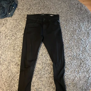Svarta jeansbyxor från Replay - Snygga svarta jeansbyxor från Replay i modellen Jondrill. De har en tight passform och är perfekta för en stilren look. Byxorna har en klassisk design med knappar och dragkedja framtill. Nypris 1500