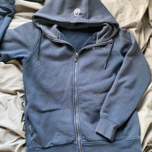 Sailracing kofta - Säljer en mörkblå Sailracing zip hoodie. 10/10 skick. Inga fläckar!  Storleken är small men jag som har medium i de flesta koftor tycker den sitter fint och slim