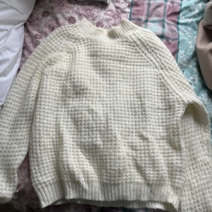 Vit stickad tröja från 157 - Mysig vit stickad tröja från 157 med en härlig textur. Perfekt för kyliga dagar med sin varma och bekväma design. Tröjan har långa ärmar och en klassisk passform. Den har använts få tal gånger. Ser och känns fortfarande jätte ny. 