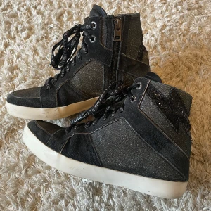 Svarta sneakers från Zadig & Voltaire - Snygga svarta sneakers med glittriga detaljer från Zadig & Voltaire. Skorna har snörning och dragkedja på sidan för enkel på- och avtagning. De har en vit sula och en cool stjärndetalj på hälen. Skriv för frågor!! ❤️‍🔥❤️‍🔥