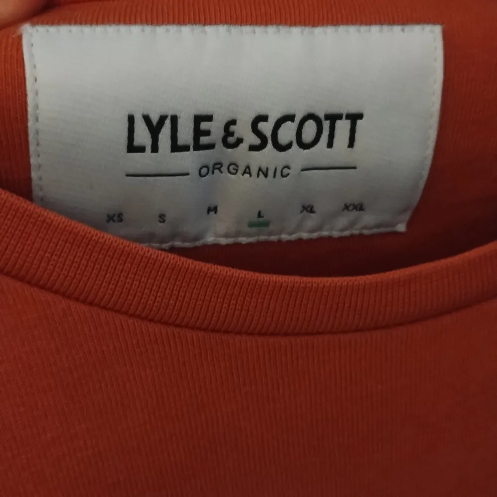 Säljer en snygg orange t-shirt från Lyle & Scott. Den är i bomull och har en liten broderad logga på bröstet. Perfekt för en avslappnad stil!. T-shirts.