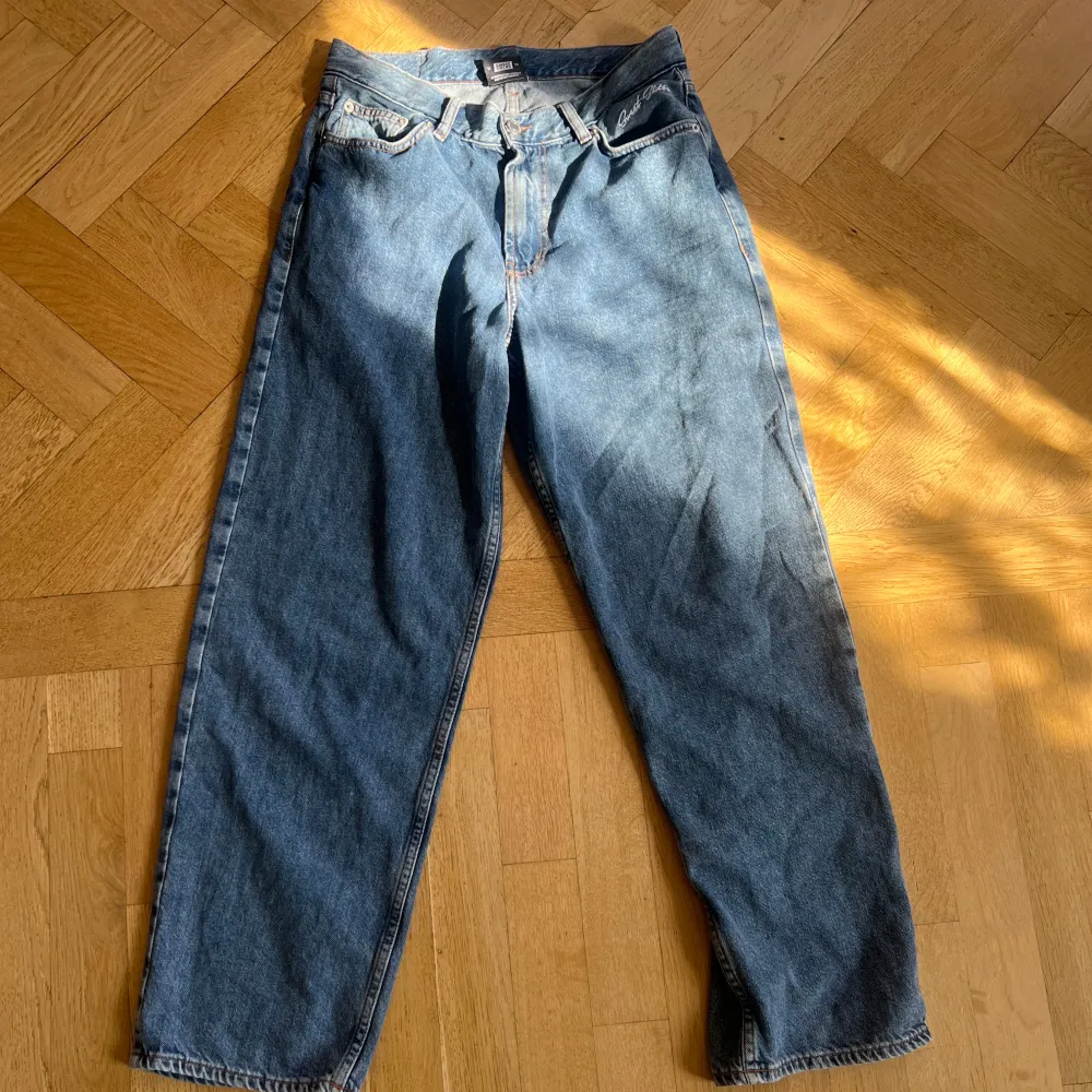 Säljer ett par klassiska blå jeans från Sweet Skts. De har en baggy passform och är tillverkade i slitstarkt denim. Perfekta för en avslappnad stil. Jeansen har fem fickor och knappar i midjan.. Jeans & Byxor.