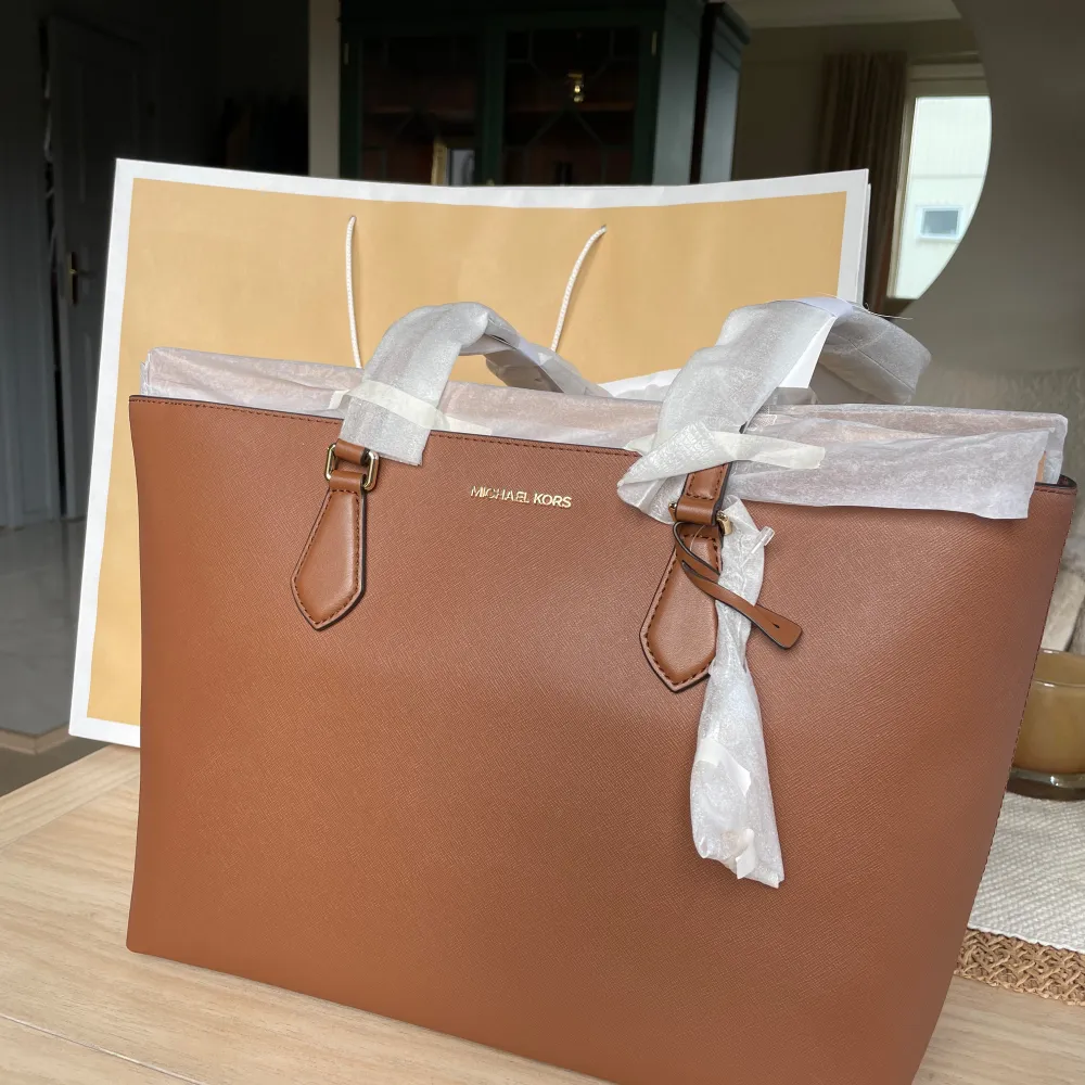 Helt ny och oanvänd brun Michael kors väska Tote Bag med laptopfack 👜 Storleken blev fel och gick tyvärr inte att lämna tillbaka Mått: 42x27cm (den större modellen) 1100kr. Väskor.