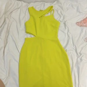 Gul klänning från Topshop - Säljer en superfin gul klänning från Topshop! Den har en unik design med cut-out detaljer och en tight passform som verkligen framhäver figuren. Perfekt för sommarens fester eller en utekväll. Klänningen är ärmlös och har en dragkedja i ryggen för enkel påklädning. Materialet känns mjukt och stretchigt. 🌟
