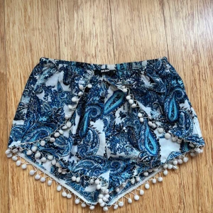 Mönstrade shorts med tofsar - Snygga blå och vita shorts från Bikbok med ett paisleymönster. De har dekorativa tofsar längs kanterna som ger en bohemisk känsla. Perfekta för sommarens varma dagar.