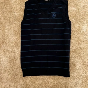 Randig väst från Kappahl - Ärmlös stickad väst i mörkblått med ljusblå ränder. V-ringning och en broderad logotyp på bröstet.  Kön: pojke Storlek: 146-152 Skick: 9/10 Ord: pris: 199  Din stil: spara inlägget så du inte missar denna kappa Inte din stil: Kolla min profil. Du kommer hitta något för alla kön och åldrar.