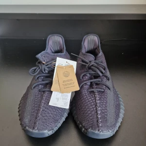 YEEZY BOOST 350 V2  - Snygga svarta Adidas Yeezy sneakers med stickad ovandel och snörning. Skorna har en robust sula med Boost-teknologi för extra komfort. Perfekta för en stilren look.Har order bekräftelse från Adidas för att bevisa att de är äkta.
