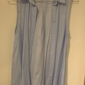 Blå- och vitrandig ärmlös skjorta från H&M Divided - Säljer en somrig blå- och vitrandig ärmlös skjorta från H&M Divided. Perfekt för sommaren.Jag bär ett M och det passar mig men jag skulle säga att det är mer av ett S. Hör av dig vid frågor😊