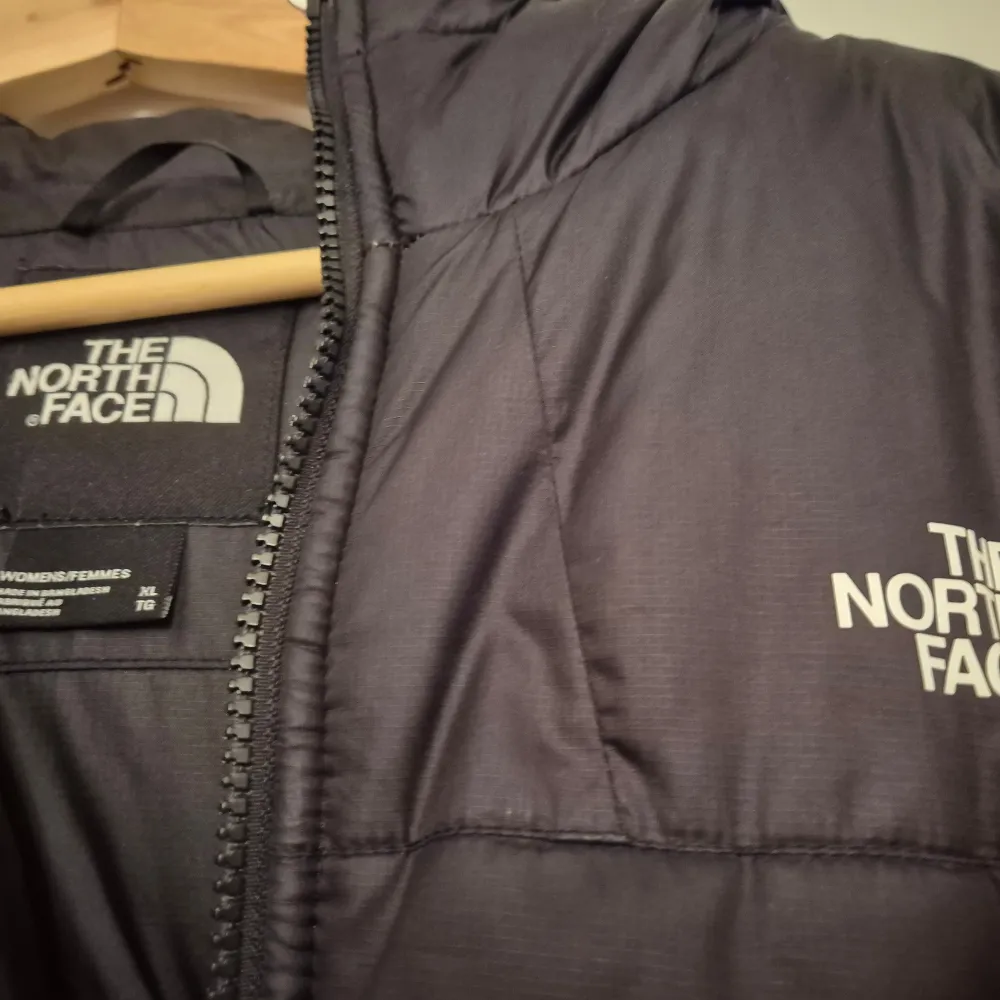 Säljer en svart dunjacka från The North Face med dragkedja och huva. Jackan har en quiltad design och är perfekt för kyliga dagar. Den har två sidofickor och logotypen på bröstet. Perfekt för vintern! 🖤. Takit.