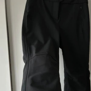 Svarta skidbyxor  - Snygga svarta skidbyxor med dragkedja och knappar framtill. De har en stilren design och är perfekta för en modern look. Passar bra till olika utomhustillfällen och är lätta att matcha med andra plagg! Använda 4 ggr 🏂❄️