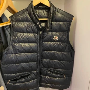 Marinblå dunväst från Moncler - En moncler väst i marinblå, inget fel på den bra skick storlek 3, ej kvitto vill ni har fler bilder är det bara att skriva. PRISET KAN DISKUTERAS 