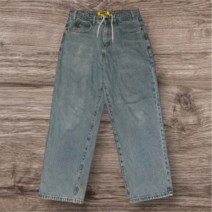 Butter goods baggy jeans - Säljer ett par baggy jeans från Butter i en klassisk blå denim. Byxorna har en avslappnad passform med snörning i midjan och coola broderade detaljer vid fickorna. De är knappt använda i bra skick