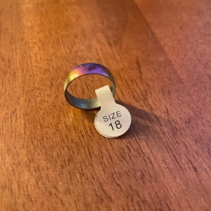 Flerfärgad ring i storlek 18 - Snygg flerfärgad ring i storlek 18. Ringen har en metallisk yta som skiftar i olika färger beroende på ljuset. Perfekt för att ge en unik touch till din stil.