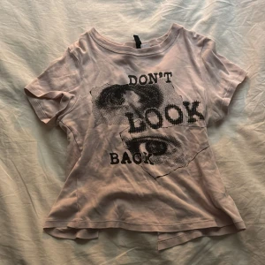 Ljus rosa t-shirt med tryck - Säljer en rosa t-shirt från H&M med ett coolt tryck som säger 'DON'T LOOK BACK'. Perfekt för en avslappnad stil. T-shirten har korta ärmar och en rund halsringning.