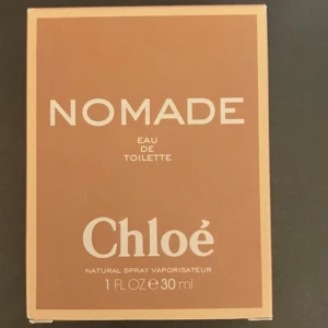 Nomade Eau de Toilette från Chloé - Nomade Eau de Toilette från Chloé i en elegant flaska med gulddetaljer och en stilren design. Flaskan rymmer 30 ml och har en lyxig känsla med en beige remsa runt halsen. Perfekt för den som söker en sofistikerad och modern doft.