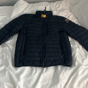 Mörkblå dunjacka från Parajumpers - Säljer en svart dunjacka från Parajumpers i superlätt material. Jackan har en hög krage med en gul detalj och flera praktiska fickor med dragkedjor. Perfekt för kyliga dagar. Äkta såklart 🙌 jag säljer den billigt för att jag behöver pengar till nya skor 