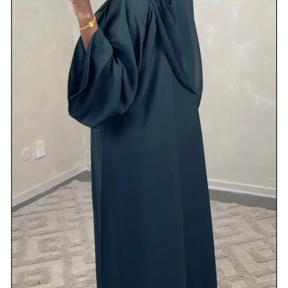 Elegant mörkgrön långklänning med vida ärmar och en flytande passform. Perfekt för en sofistikerad look. Köpt från luude, perfekt för sommar skön och kylig.. Mekot.