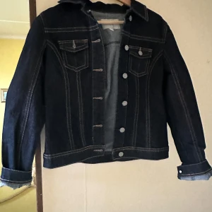 Mörkblå jeansjacka från Mywear Woman - Säljer en snygg mörkblå jeansjacka från Mywear Woman i storlek 38. Jackan har långa ärmar och knappar framtill samt två bröstfickor med lock. Perfekt för en casual look! 💙