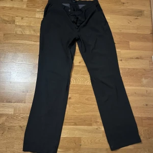 Gråa kostymbyxor från Filippa K - Snygga gråa kostymbyxor från Filippa K med en klassisk design. Byxorna har en rak passform och är tillverkade i ett elegant material. Perfekta för en stilren look.