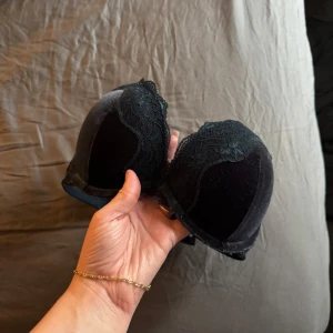 Svart spets-bh - Snygg svart bh med spetsdetaljer. Den har vadderade kupor och justerbara axelband för bästa passform. Perfekt för att känna sig både bekväm och elegant.