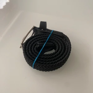 Svart flätat bälte  - Snyggt svart flätat bälte från Kappahl med en stilren silverfärgad spänne. Perfekt för att ge en extra touch till din outfit. Bältet är 75cm och passat bra till jeans. Endast använd 1 gång